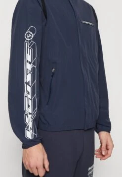 Lacoste Regenjas - Bleu 12 Lacoste Regenjas - Bleu -Mode Kledingwinkel b63abd724bbb4904944a82469e81cbd5